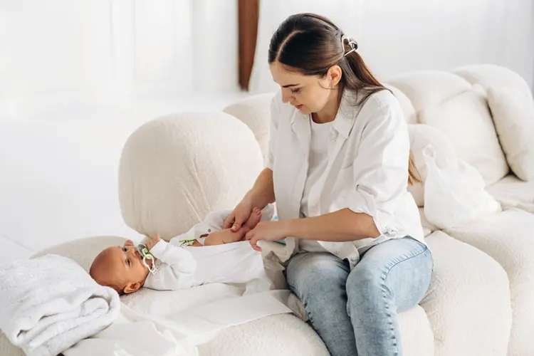 Parent changing newborn baby on soft fabric